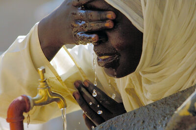 In Afrika schöpft eine Frau Trinkwasser vom Hahn