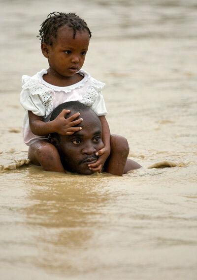 Ein Mann trägt sein Kind durch Wasserfluten