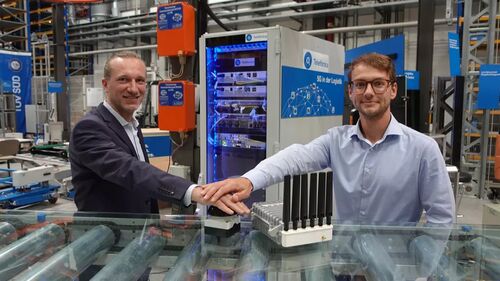 Frank Schmidt-Künzel von O2 Telefónica und Leonhard Feiner, Teamleiter am Lehrstuhl Fördertechnik Materialfluss Logistik der TUM nehmen das 5G-Campusnetz in Betrieb.