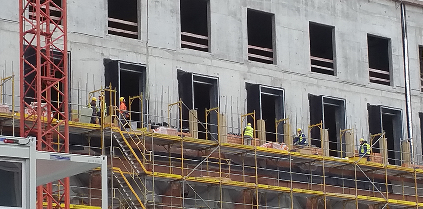 Auf einer Großbaustelle arbeiten Bauarbeiter auf einem Gerüst.