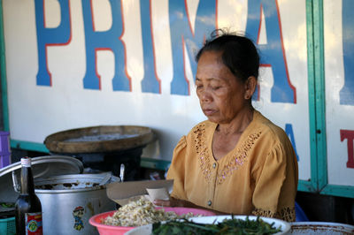Eine balinesische Frau bereitet auf dem Markt das Essen vor.