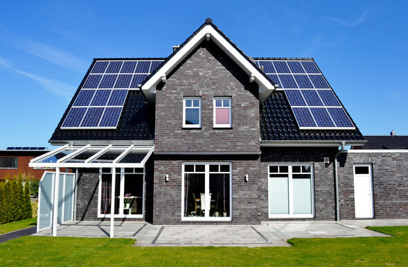 Ein Einfamilienhaus mit Solardach unter blauem Himmel