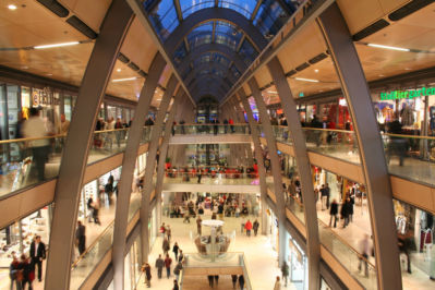 Ein einem großen beleuchteten Einkaufszentrum shoppen viele Verbraucher.