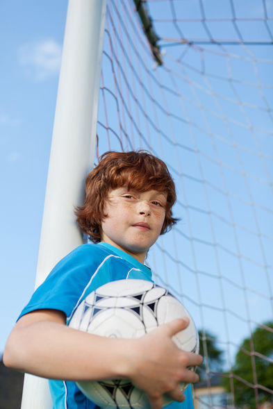 Ein Junge mit einem Fußball im Fussballtor