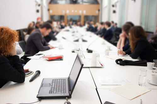 Bei einem Meeting sitzen Manager mit Laptop an einem Konferenztisch.