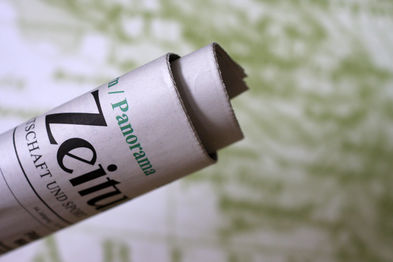 Eine Zeitungsrolle vor einer Weltkarte