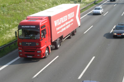 Ein roter LKW fährt auf der Autobahn.