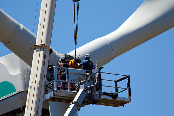 Männer arbeiten an einer Windkraftanlage.