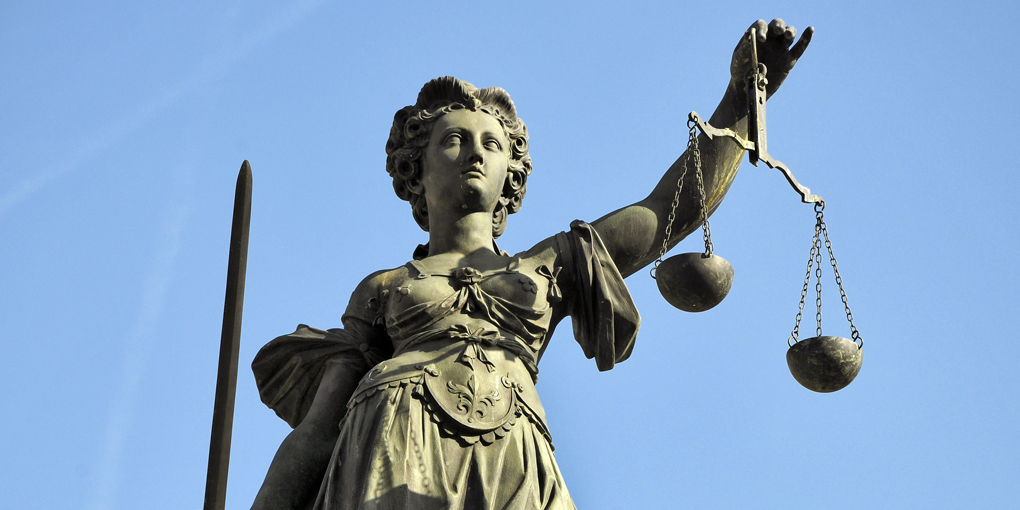 Eine Justizia-Statue vor blauem Himmel