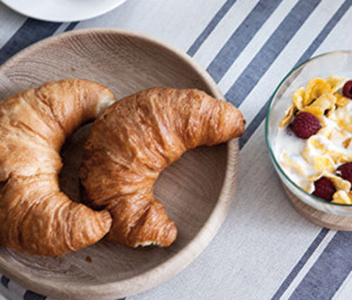 Ein Frühstückstisch mit zwei Croissants und Müsli.