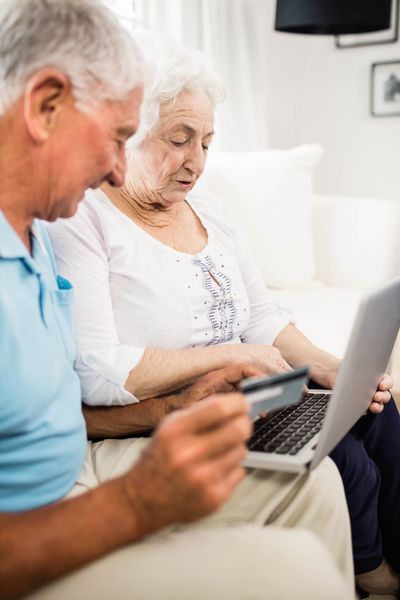 Senioren bedienen zusammen einen Laptop