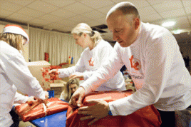 DPD Mitarbeiter packen mit an und schnüren Weihnachtspakete für die Aktion „Leuchtende Kinderaugen“. Mit dabei waren auch DPD Geschäftsführer John Acton (rechts) und Verena Hilss, Director Network Marketing (Mitte). Foto: DPD